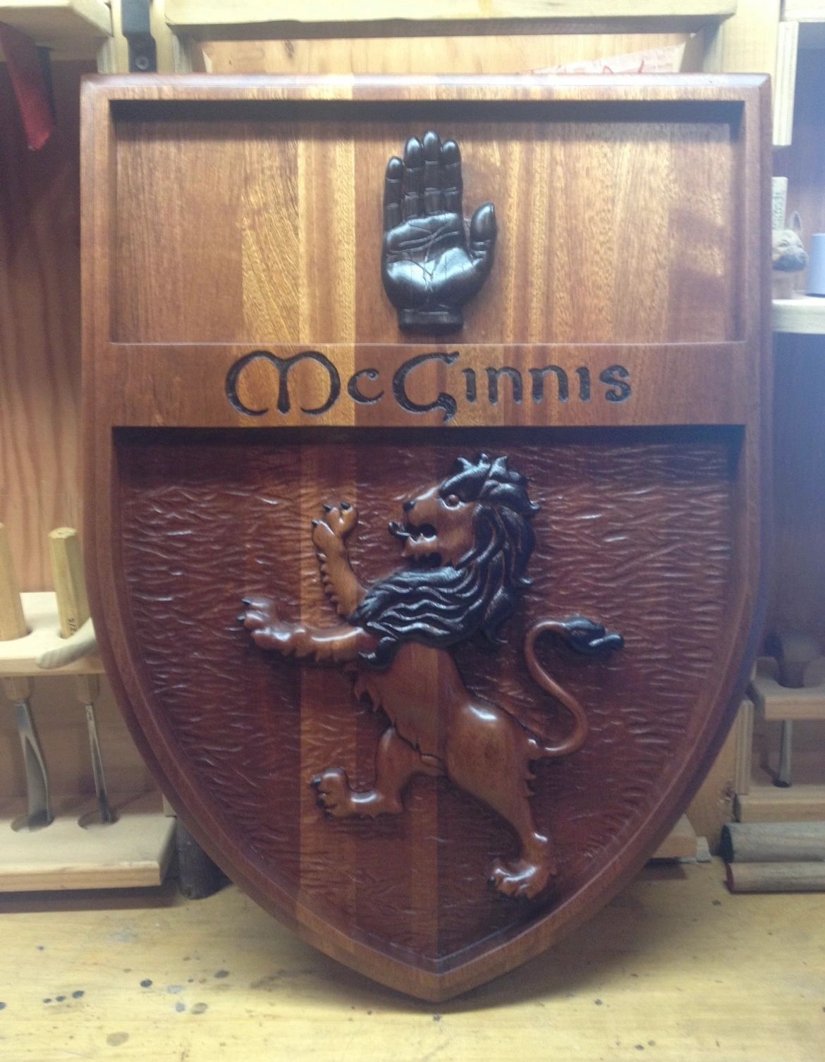 Carved wooden family crest with a rampant lion and the name McGinnis