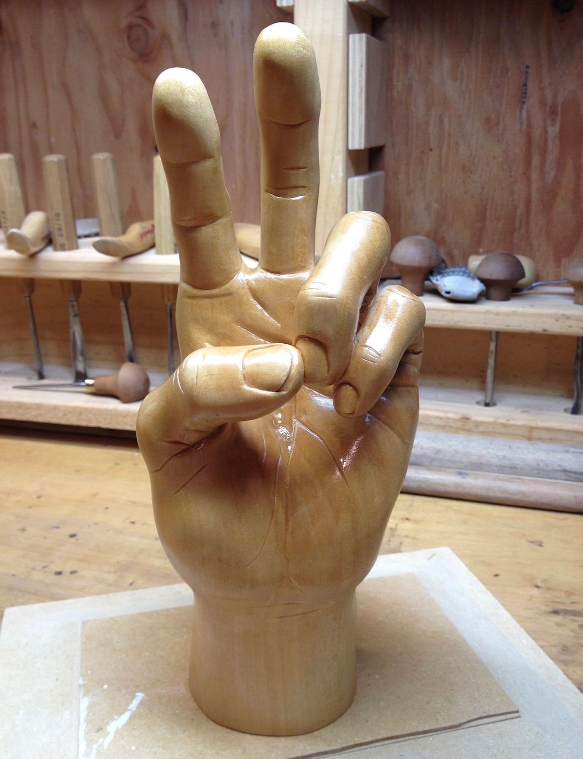 A hand making a peace sign, carved from a single block of wood