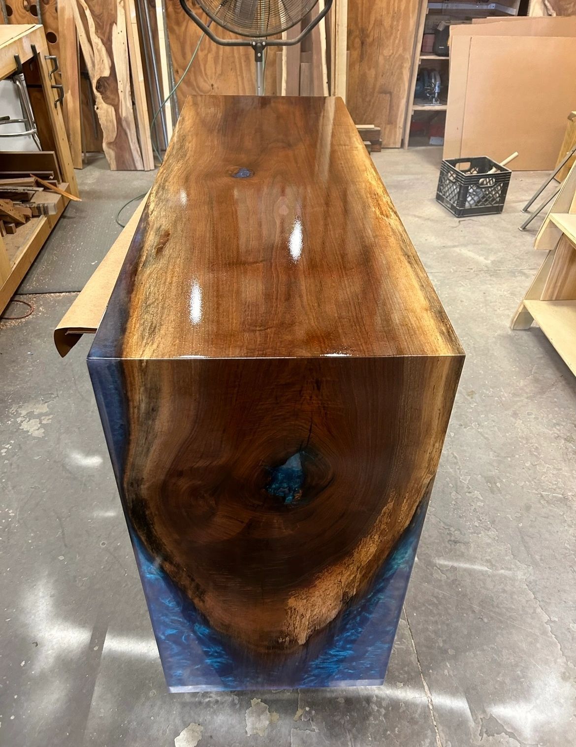 Black walnut waterfall bar with a blue resin-filled void, glossy finish, in Steve Sushko's workshop